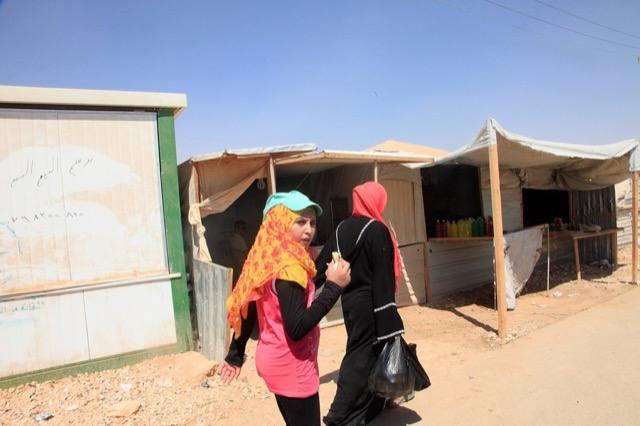 Two Syrian refugee women walk past market stalls in the Za&rsquo;atari refugee camp in northern Jordan.