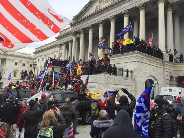 A crowd with flags storms the steps of the United States Capitol on January 6, 2021.